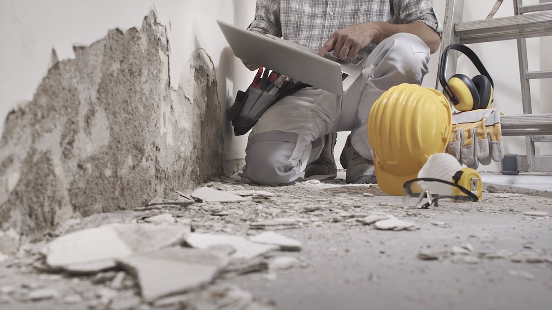 Restoration project manager reviewing job progress on a laptop on the job site