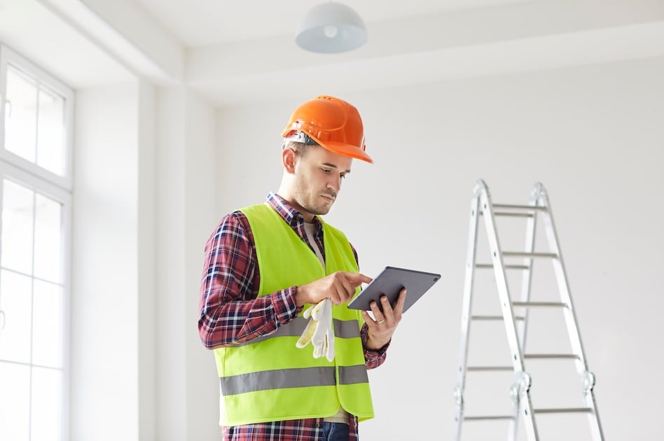 Project manager using a tablet to schedule crews at a restoration job site.