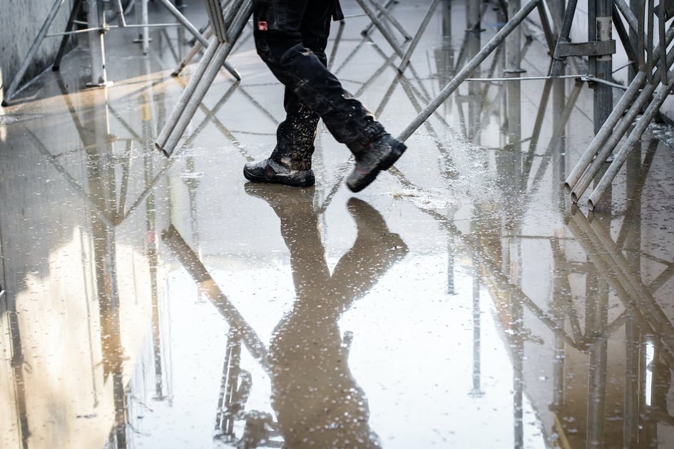 Restoration worker walking on wet concrete.